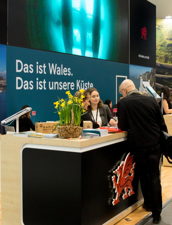 People talking at a stand in a travel trade show.