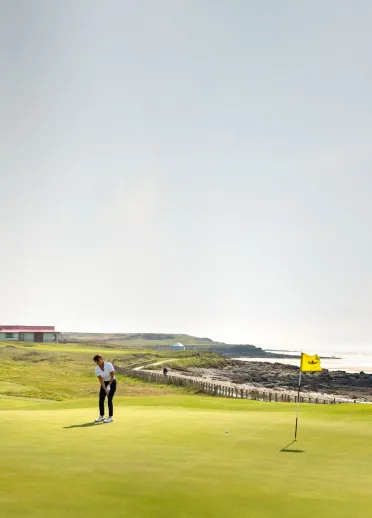 Woman playing golf at the Royal Porthcawl Golf Club, South Wales