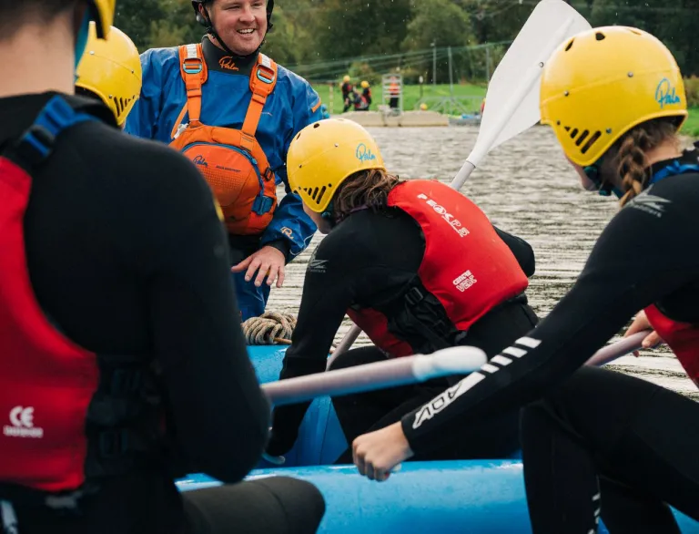 A white water rafting instructor guides a group of visitors down the rapids at White Water Rafting, Llandysul.