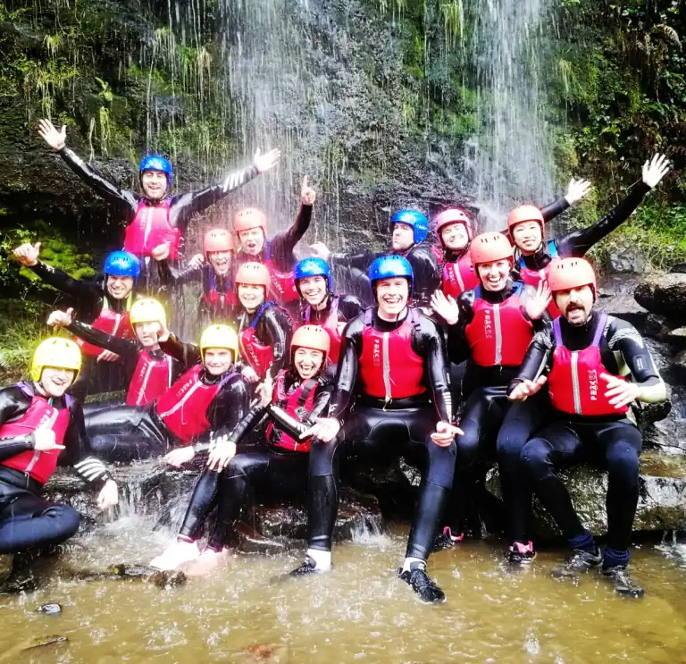 A group wearing safety clothing under a waterfall.