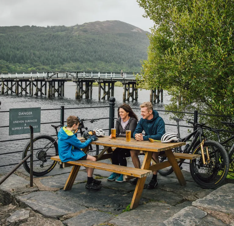 Family with bikes sat at picnic bench, Mawddach Trail