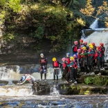 A group of people in safety gear diving near a waterfall.