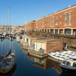 Looking across Milford Haven marina waterfront to boats, floating glamping pods and buildings