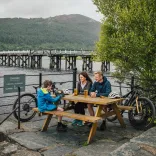Family with bikes sat at picnic bench, Mawddach Trail